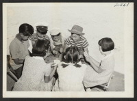 [recto] A group of children evacuees enjoying a game of Black Jack at this War Relocation Authority center. ;  Photographer: Stewart, Francis ;  Poston, Arizona.
