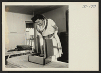 [recto] Closing of the Jerome Center, Denson, Arkansas. Mitzi Matsunaga packs her dresses just prior to her departure to the Rohwer Center. All that remains are the cots, blankets and stove furnished by the government. ;  Photographer: Iwasaki, Hikaru ;  Dens