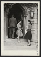 [recto] Marie Kitazomi (left), from the Tule Lake Center, is seen with Monica Itoi from Minidoka at the entrance to a church where they attend services. Both girls are employed as secretaries in the city and Miss Itoi expects to enroll in Hanover College this fal