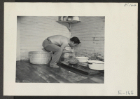 [recto] Farmhouse quarters for beet worker volunteers did not always include bathrooms. Chihiro Sugi does his evening washing in a typical makeshift arrangement. ;  Photographer: Parker, Tom ; , .