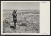 [recto] Carl Bigelow, cameraman from the Oakland Tribune, photographs a general view of The Tule Lake Relocation Center. ;  Photographer: Stewart, Francis ;  Newell, California.