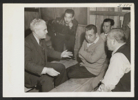 [recto] Dr. P. A. Weber, from the WRA office in Salt Lake City, who speaks fluent Japanese, talks with some of the evacuees during the visit of a Relocation Team to the Rohwer Project. ;  Photographer: Van Tassel, Gretchen ;  McGehee, Arkansas.