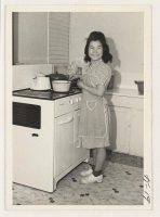 [recto] May Shimada, Rt. 1, box 366A, Acampo, California, cooking at the newly purchased range which was secured by a priority ...