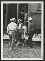 [recto] W.R.A. wardens, stationed at Tule Lake, help passengers to alight from the coaches on arrival at the Tule Lake Center. ;  Photographer: Mace, Charles E. ; , .