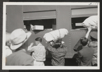 [recto] Passing luggage into train through windows at the Delta station. ;  Topaz, Utah.
