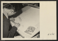 [recto] A young Nisei artist in the Poster Shop at the Heart Mountain Relocation Center prepares the final sketch on a poster, which is part of the drive at the center to save rubber. ;  Photographer: Parker, Tom ;  Heart Mountain, Wyoming.