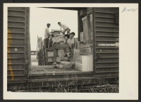 [recto] Closing of the Jerome Center, Denson, Arkansas. Evacuee workers load a freight car with the crated possessions of Jerome residents being transferred to Gila River. ;  Photographer: Mace, Charles E. ;  Denson, Arkansas.