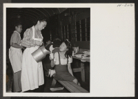 [recto] A volunteer waitress pours a cup of iced tea for one of the many children dining in the improvised box car. ;  Photographer: Mace, Charles E. ; , .
