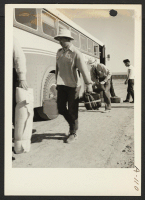 [recto] Site No. 1. Caucasian employees assist evacuees with the unloading of their baggage from the bus which has just arrived at the relocation center for evacuees of Japanese ancestry. ;  Photographer: Clark, Fred ;  Poston, Arizona.