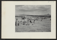 [recto] Crates of personal belongings are sorted in the central square at this relocation center . Individual owners identify their belongings and provide addresses for delivery of the crates to their barracks. ;  Photographer: Parker, Tom ;  Heart Mountain,