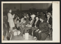 [recto] Seated in family groups, evacuees of Japanese ancestry check in at the Armory before moving to an assembly center. They will be transferred later to a War Relocation Authority center. ;  Photographer: Albers, Clem ;  Salinas, California.