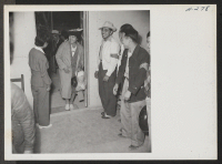 [recto] Volunteer wardens, at the Topaz Center, are shown meeting new arrivals as they enter the induction center, where they direct them to the various departments. ;  Photographer: Mace, Charles E. ;  Topaz, Utah.