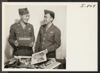 [recto] S/Sgt. Henry H. Gosho, left, and Pfc. James Yura, right, are seen looking over War Relocation Authority photographs of some ...