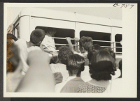 [recto] A young Nisei bids goodbye to his friends just before the bus starts for Gila River Relocation Center, August 24, ...