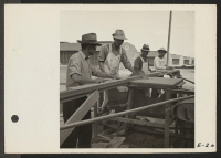 [recto] A group of carpenters using a power saw in preparing pieces for completing the interiors of barracks at Topaz. ;  Photographer: Parker, Tom ;  Topaz, Utah.