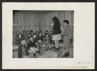 [recto] A student acting as teacher in a second grade class of the Rohwer Relocation Center grammar school. The assistant teacher ...