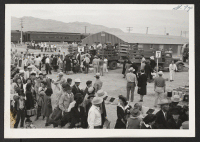 [recto] Foreground--line awaiting induction. Background--boarding trucks to be transported to their barracks. INCOMING ;  Photographer: Aoyama, Bud ;  Heart Mountain, Wyoming.