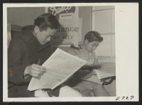 [recto] When the Sentinel weekly newspaper, of the Heart Mountain Relocation Center, hits the newsstands, the rush is on. The two young Nisei shown here had to read the sports page before they could leave the community store. ;  Photographer: Parker, Tom ;  H