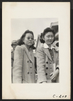 [recto] School girls await evacuation bus. Evacuees of Japanese ancestry will be housed in War Relocation Authority centers for the duration. ;  Photographer: Lange, Dorothea ;  Centerville, California.
