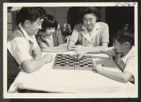 [recto] A successfully relocated Nisei family is portrayed in this picture of the Harry Taketa family. As father plays a game ...