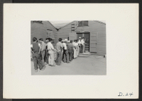 [recto] Tule Lake, Newell Calif.--A line up of evacuee workers waiting for their identification tags which are to be used in conjunction with the first pay day at this War Relocation Authority Center. ;  Photographer: Stewart, Francis ;  Newell, California.