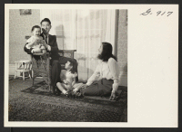 [recto] Mr. and Mrs. Kengitsu Iijima with their daughters, Aileen and Lillian, at home in their three-room apartment at 39 Wadsworth ...