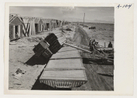 [recto] Site No. 1. Unloading lumber with bulldozer in the construction of barracks for evacuees of Japanese ancestry who will spend the duration in War Relocation Authority centers. ;  Photographer: Clark, Fred ;  Poston, Arizona.