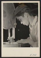 [recto] In the center cabinet shop, where office and school furniture is being prepared, K. Inouye, a former Californian, operates a band saw. ;  Photographer: Parker, Tom ;  Denson, Arkansas.
