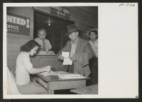 [recto] In the induction center at Tule Lake, one of the 489 arrivals on trip 15 from Topaz is seen receiving his new barracks number from one of the clerks before being issued his quota of blankets. ;  Photographer: Mace, Charles E. ; , .
