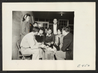 [recto] Members of the Little Theatre Group, under the direction of instructor Derlan (right), prepare their ticket selling campaign for their first play presentation. ;  Photographer: Parker, Tom ;  Amache, Colorado.