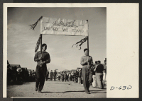 [recto] Two of the evacuees carrying the J.A.C.L. banner in the Harvest Festival Parade held at this center on Thanksgiving day. ;  Photographer: Stewart, Francis ;  Rivers, Arizona.