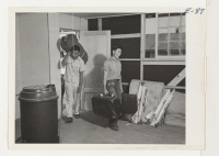 [recto] Young evacuees carrying their personal belongings into their new quarters at this relocation center just getting under construction. ;  Photographer: Parker, Tom ;  Amache, Colorado.