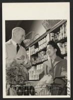 [recto] Mrs. Verlin Yamamoto, formerly of San Francisco and Gila River Center, buys her Saturday groceries at a modern meat and food market located near her home, 3920-1/2 Grand Avenue, Des Moines, Iowa. ;  Photographer: Iwasaki, Hikaru ;  Des Moines, Iowa.