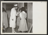 [recto] New arrivals from Tule Lake are shown entering the induction center where they are first met by a nurse and nurses' aids who checked their medical records. ;  Photographer: Mace, Charles E. ;  Topaz, Utah.