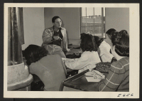 [recto] Bill Hosokawa, Editor of the Sentinel, Heart Mountain Relocation Center newspaper, a Washington U. graduate, and former west coast newspaper man and foreign correspondent, conducts a biweekly class in journalism for the reporters of his Sentinel staff.
