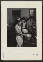 [recto] The beet workers look over the shoulder of the chef for the day as he prepares the evening meal. These Nisei boys are members of a crew of volunteer beet workers who helped in the harvest of sugar beets near Billings, Montana. ;  Photographer: Parker, T