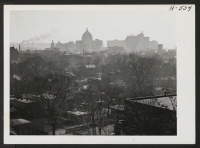[recto] Looking across the downtown district of Peoria from the west, one sees the tall hotels and buildings in the heart of the town, as they push up through the smoke of Peoria's industries. ;  Photographer: Mace, Charles E. ;  Peoria, Illinois.