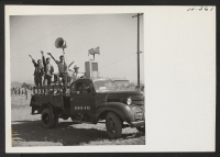 [recto] The public address system broadcasts records as trains arrive at and depart from the Tule Lake Center. Operators of the truck wave farewell to former friends entraining at Heart Mountain as the loud speakers carry the strains of Aloha. ;  Photographer: