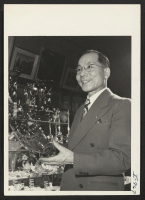 [recto] Harry S. Oshimo, an Issei resident of Kansas City for ten years, in his gift shop on Petticoat Lane in ...