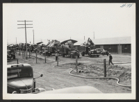[recto] OUTGOING--Baggage trucks waiting to load train. ;  Photographer: Aoyama, Bud ;  Heart Mountain, Wyoming.