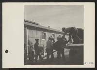 [recto] A crew delivering U.S. Army No. 1 Space Heaters to a resident barracks at the Topaz Center. ;  Photographer: Parker, Tom ;  Topaz, Utah.