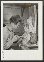 [recto] In a wood carving class, this center resident, a former Californian of Japanese ancestry, works on a patriotic carving cut from a natural hardwood formation. ;  Photographer: Parker, Tom ;  McGehee, Arkansas.