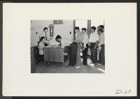 [recto] Tule Lake, Newell, Calif.--May Minyamoto, executive clerk, and Hyrum L. Clark, project personnel clerk, distribute identification tags to be used in conjunction with the first pay day at this War Relocation Authority center. ;  Photographer: Stewart, Fr