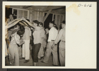 [recto] Evacuees of Japanese ancestry dance the Virginia Reel at a barn dance given by Block 12. No music was available so dancers sang pop goes the Weasel and clapped hands in time with the dance. ;  Photographer: Stewart, Francis ;  Poston, Arizona.