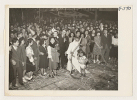 [recto] Evacuees celebrate New Year's Eve. Japanese-Americans at Central Utah Relocation Center celebrated reopening of the West Coast with a big New Year's Eve party. Joseph Aoki portrays Father Time and his son, Tommy, Baby New Year. ;  Photographer: Mace, Ch