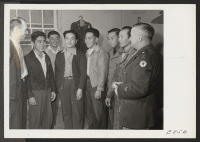 [recto] Ray D. Johnston, left, center director, and Captain John A. Holbrook, chief of an army recruiting team, discuss army with a group of volunteers and Sergeant Isamu Adachi, at the Rohwer Relocation Center. ;  Photographer: Parker, Tom ;  McGehee, Arkans