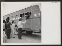 [recto] Old friends part as one of the buses loaded with passengers for Tule Lake (trip 15) is about to leave the Topaz Center. ;  Photographer: Mace, Charles E. ;  Topaz, Utah.