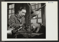 [recto] George Makanishi, evacuee from Anaheim, California, is shown at work on an engine lathe in the shop here. George is a graduate of the Fullerton Junior College, where he studied machine shop work. ;  Photographer: Stewart, Francis ;  Poston, Arizona.