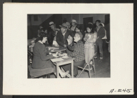 [recto] Salinas, Calif.--The head of a family of Japanese descent checks in with clerks at this assembly center prior to transfer to a War Relocation Authority center. ;  Photographer: Albers, Clem ;  Salinas, California.