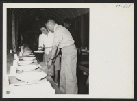 [recto] Meals aboard the segregation train were excellent and included soup and dessert. Here two volunteer helpers are placing a generous helping of canned peaches on each plate. ;  Photographer: Mace, Charles E. ; , .